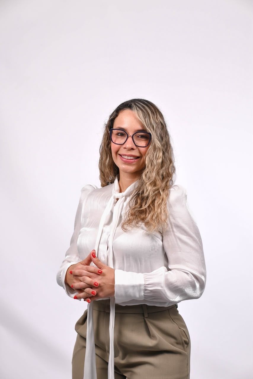 Fabiola Soriano sonriendo, con blusa blanca y lentes, en retrato profesional